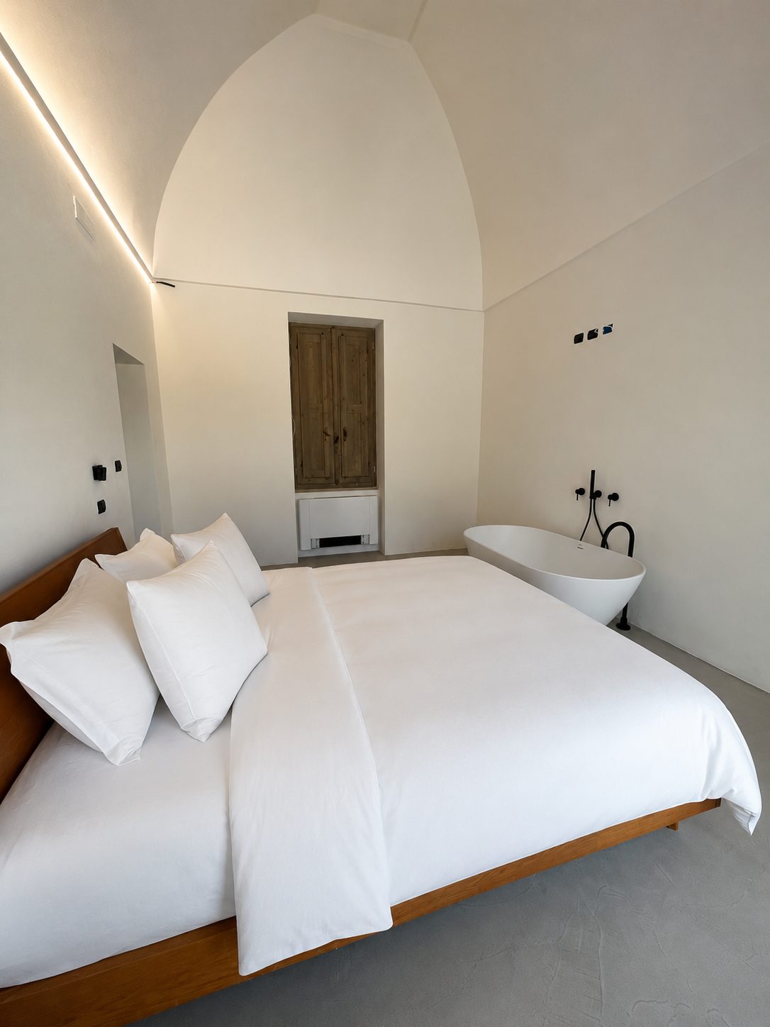 The vaulted master bedroom of Casa Andrea with a freestanding tub, lime-plaster walls, Puglia.