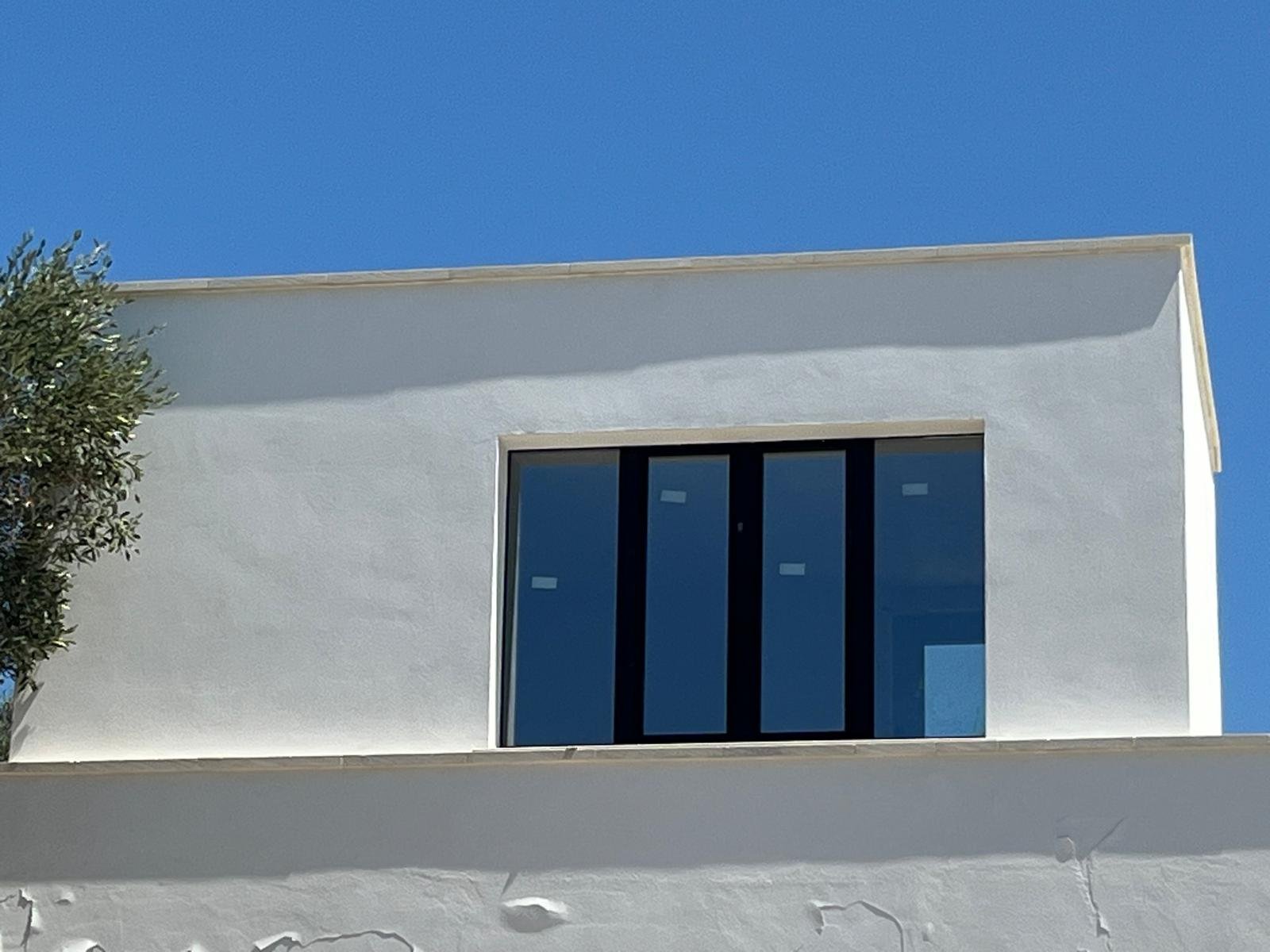 Le bureau indépendant sur le toit, au-dessus du salon de Casa Andrea — bureau près de la fenêtre, la piscine visible en contrebas, l'oliveraie de l'autre côté, Pouilles.