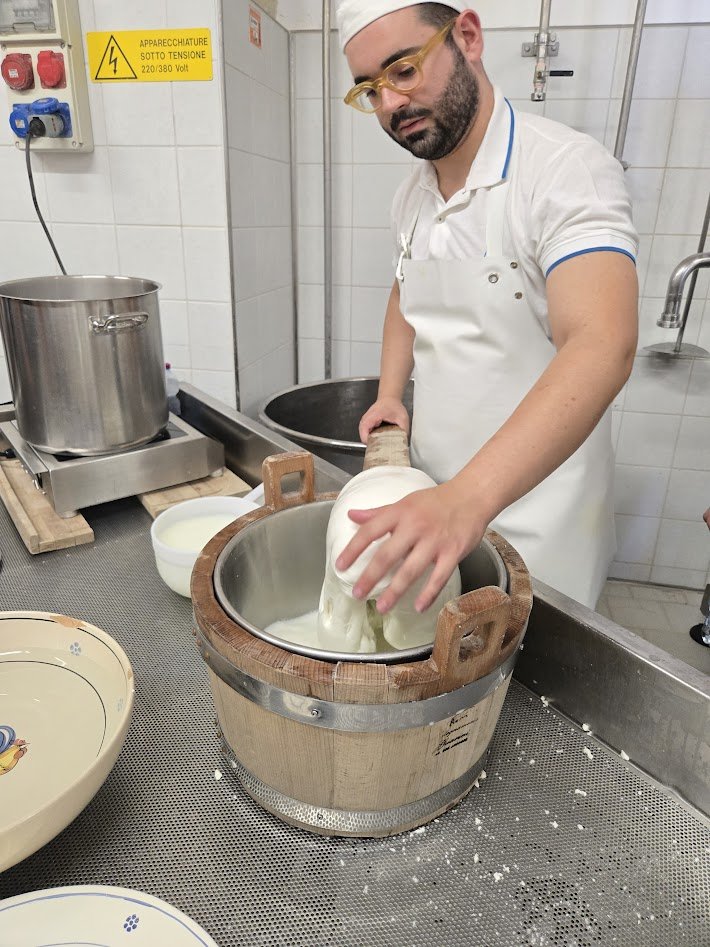 Un fromager pugliese étirant à la main une burrata fraîche pour les invités de Casa Andrea, villa lente des Pouilles près d'Ostuni.