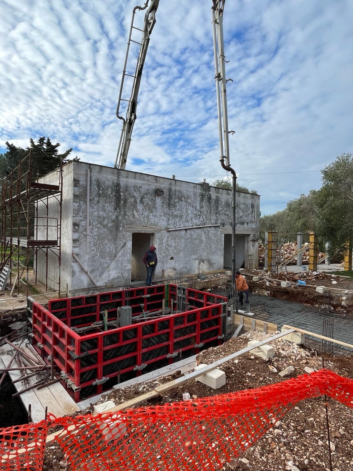 Le premier jour du chantier de Casa Andrea, février 2024 — le casale se tient restauré en arrière-plan, le premier coulage de béton est en cours, seule l'aile d'origine existe encore.